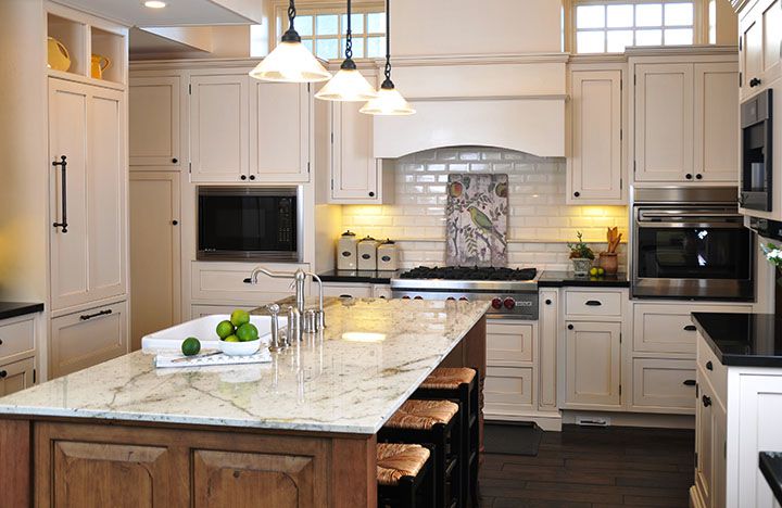 A kitchen with white cabinets and granite counter tops.