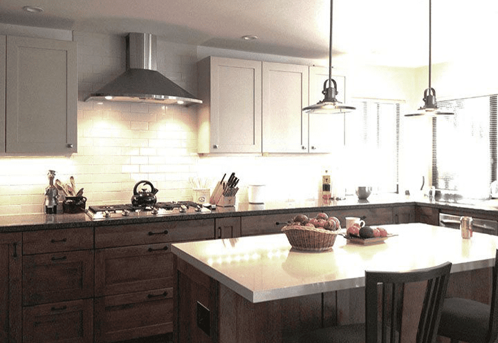 A kitchen with white cabinets and brown wood island.
