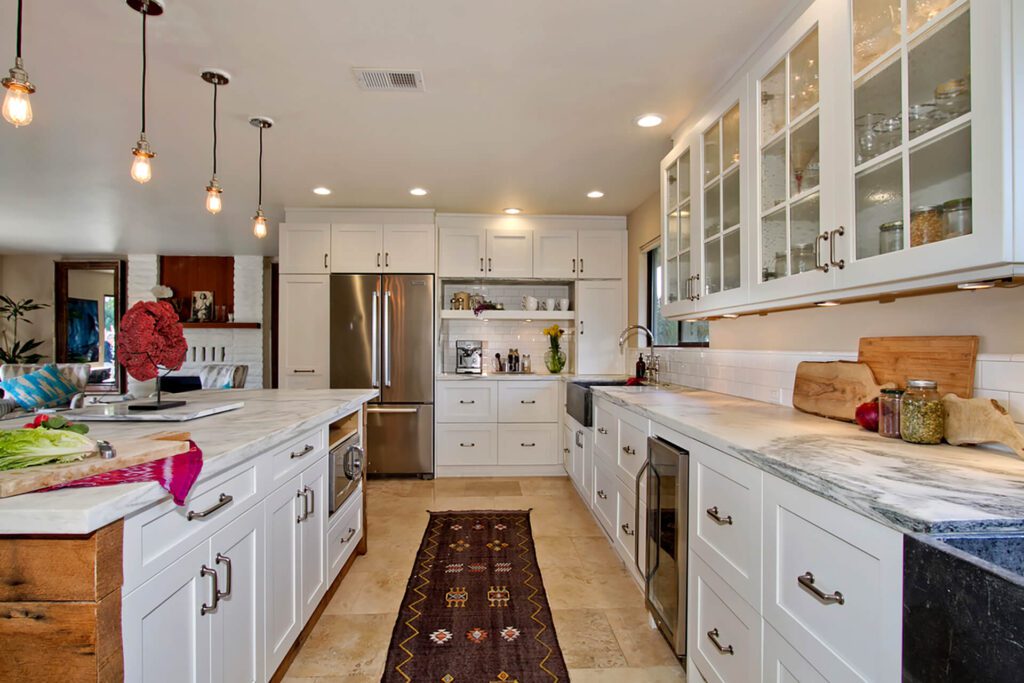 A kitchen with white cabinets and a rug on the floor.